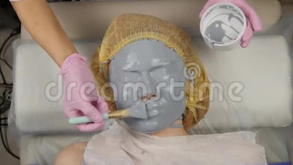 美容师在水疗沙龙为女性脸涂抹泥面膜面部年轻化程序水疗视频的预览图