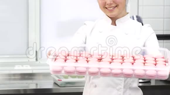 一个面点厨师用粉红色的马卡龙笑着伸出托盘视频的预览图