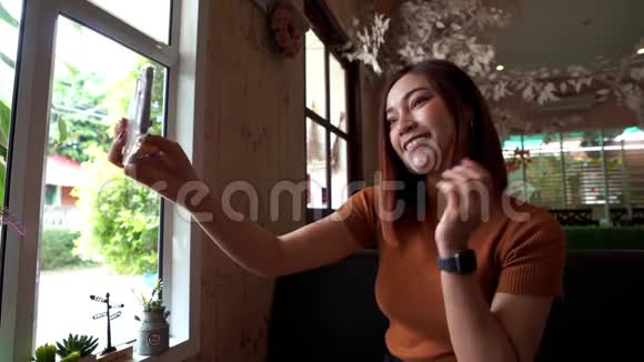 女人在咖啡馆里用智能手机自拍视频的预览图