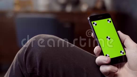 男人在家里使用移动智能手机库存录像一个男人手里拿着绿色屏幕的手机视频的预览图
