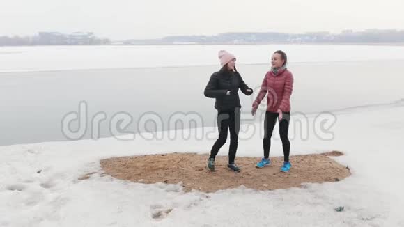 两个苗条的女人站在雪地上热身视频的预览图