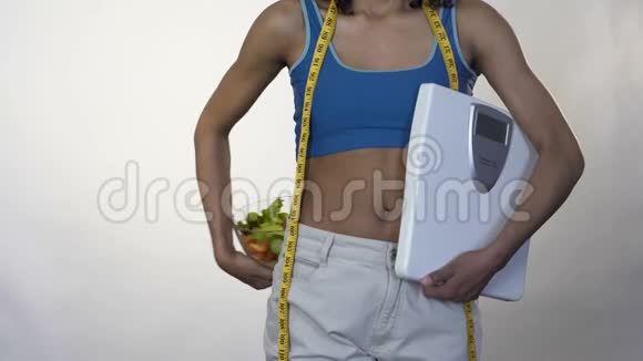 穿着宽松裤子的女人站着拿着一碗沙拉节食视频的预览图