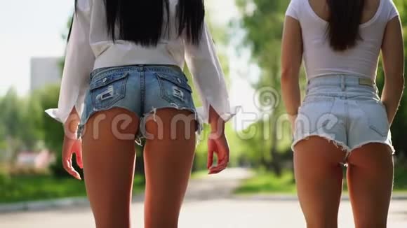 在公园里两个穿着短短裤的女孩骑着一辆自动平衡的滑板车从后视镜里看到镜头视频的预览图