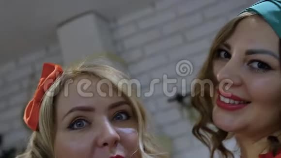 两个漂亮的女人穿着针式的衣服金发碧眼的黑发美女在智能手机上自拍视频的预览图