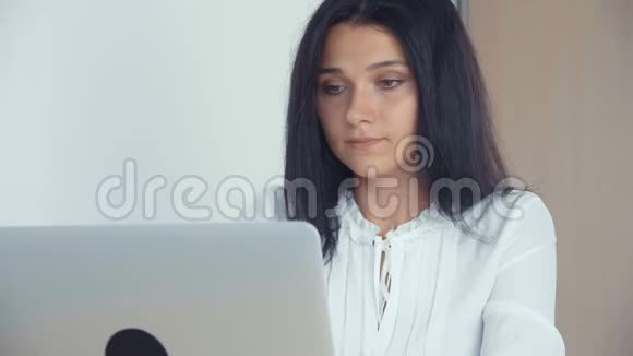 一位年轻成功的商务女孩在办公室工作使用笔记本电脑视频的预览图