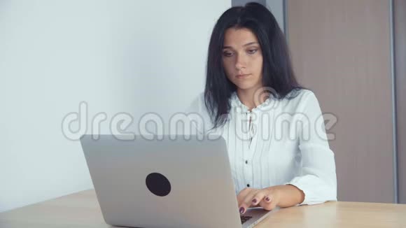 一位年轻成功的商务女孩在办公室工作使用笔记本电脑视频的预览图