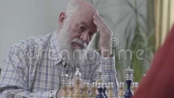 老朋友下棋坐在家里的皮革沙发上蓄胡子的人在想哪个棋子能动视频的预览图