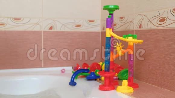 男孩从浴室里彩色设计师的塑料滑梯上滚球视频的预览图