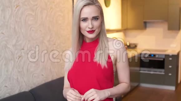 时尚优雅的金发女人在家客厅里穿着红色性感的裙子视频的预览图