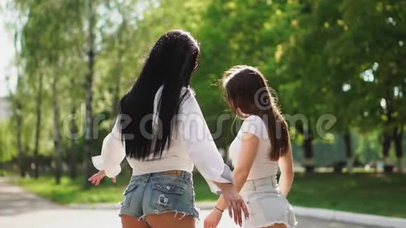 在公园里两个穿着短短裤的女孩骑着一辆自动平衡的滑板车从后视镜里看到镜头视频的预览图