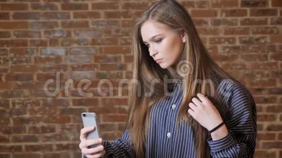 年轻漂亮的女孩正在智能手机上自拍交流理念砖背景视频的预览图