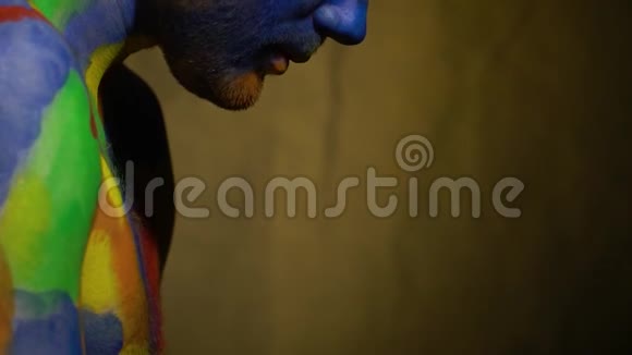 一种抽象的射击用一种多色的身体艺术拍摄一个留胡子的人他抬起头看着一边视频的预览图