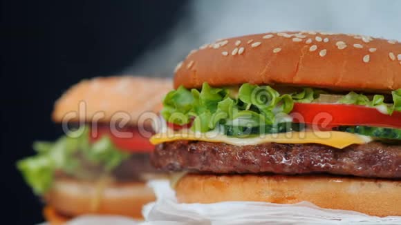 新鲜美味的烤汉堡在黑烟背景上旋转肉类西红柿黄瓜生菜和芝麻视频的预览图