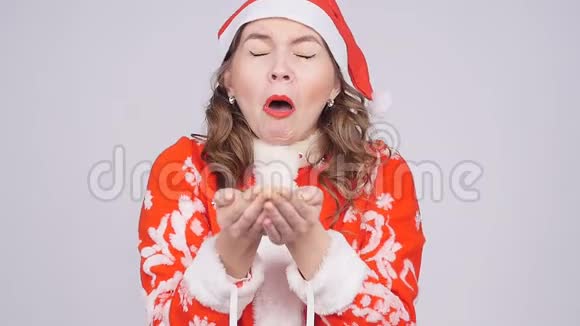 一个戴着圣诞老人帽子的滑稽年轻女子对着纸屑打喷嚏视频的预览图