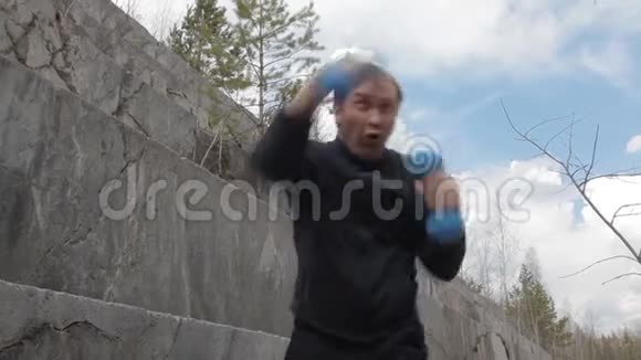 男运动员在大理石采石场用哑铃训练徒手格斗视频的预览图