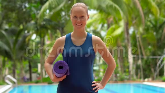 练习瑜伽的年轻女子站在游泳池前手掌在背景中看着摄像机视频的预览图
