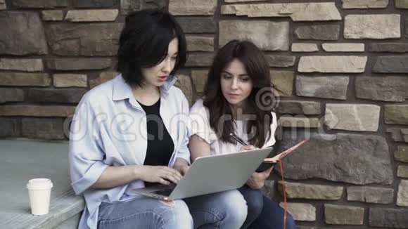 两个年轻女人带着笔记本电脑在外面工作视频的预览图