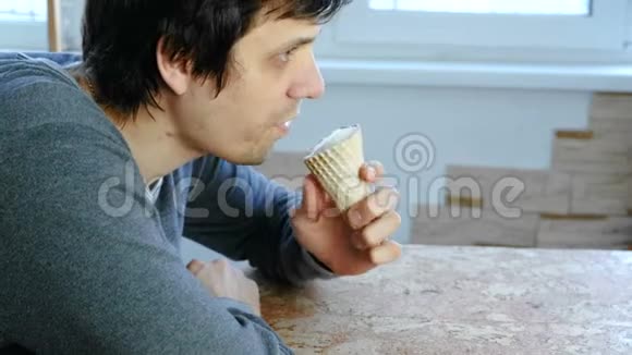 年轻人坐在窗边在家吃冰淇淋侧视视频的预览图