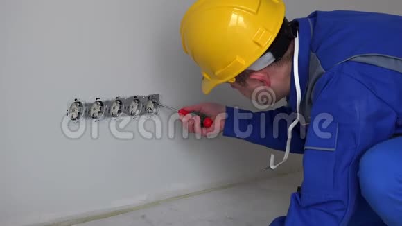 熟练工人带头盔用电压表测试墙壁插座视频的预览图