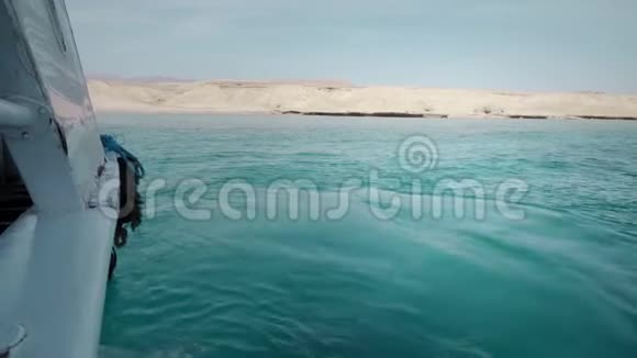 一艘载有乘客的游艇在岩石沙漠海滩的背景下潜水和钓鱼视频的预览图