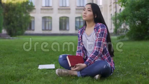 体贴的亚洲女学生独自坐在草坪上思念父母视频的预览图