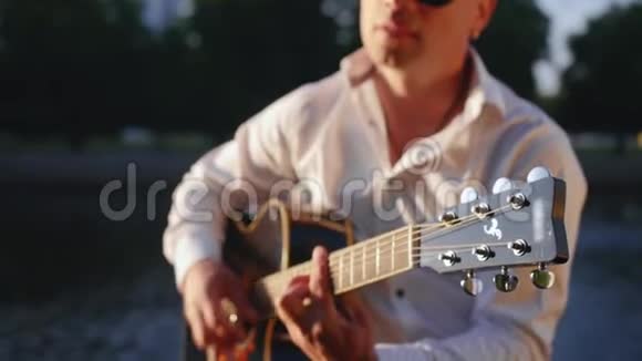 人在公园里弹吉他对着湖边唱歌吉他手触摸吉他弦中弹视频的预览图