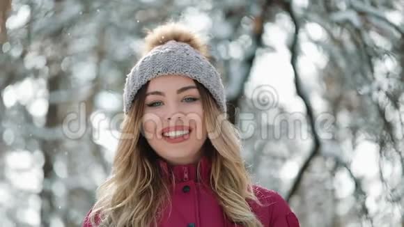 一位金发碧眼的年轻女子的画像戴着冬日户外运动帽微笑着快乐地看着镜头视频的预览图