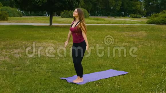 年轻漂亮的女人在夏季公园的户外训练中冥想她感到平静做瑜伽的运动女孩视频的预览图