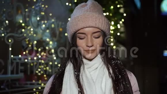 美丽迷人的女孩站在一家装饰着圣诞灯的橱窗商店旁边看着相机咖啡视频的预览图