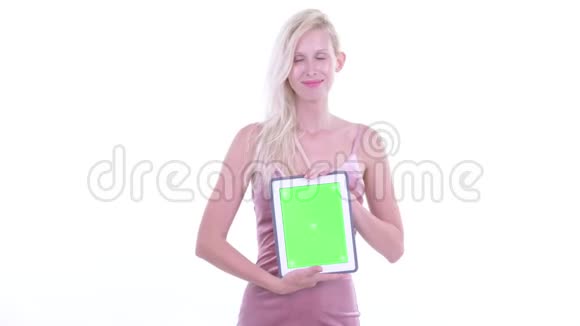 一位年轻漂亮的金发美女一边看着数码平板电脑一边思考视频的预览图