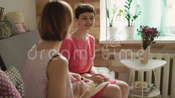 穿着针织衫的女性朋友坐在后窗的沙发上聊天视频的预览图