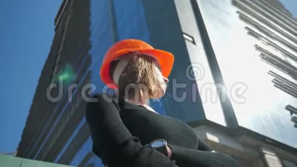 夏季白天戴着头盔的年轻女建筑工人双臂交叉站立建筑理念城市理念视频的预览图