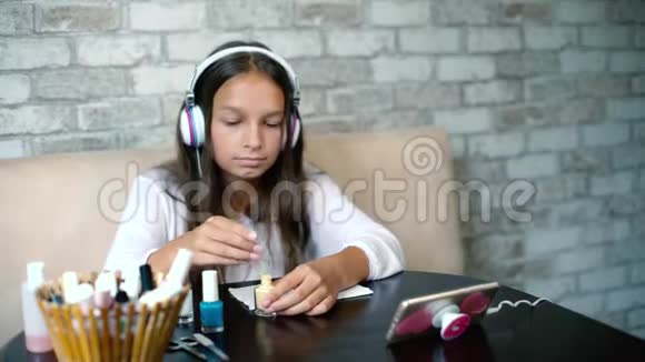 耳机里的女孩听着音乐在手机上做指甲涂抹指甲油免费复印空间视频的预览图