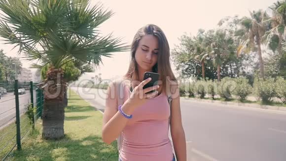 热带度假胜地夏季使用智能手机的城市街头年轻美女画像视频的预览图