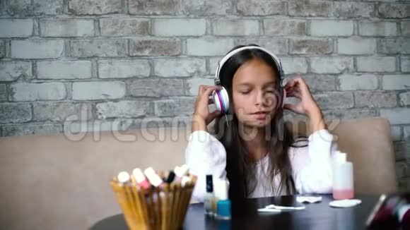可爱的女孩戴着耳机和家庭服装一边听音乐一边唱歌一边做指甲视频的预览图