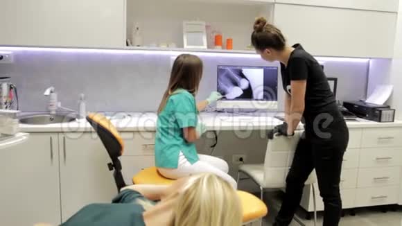 一位牙医和她的助手在谈论一个病人的X光牙齿视频的预览图