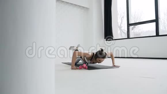 健身金发女人穿着白色运动服在健身房锻炼运动女孩做俯卧撑运动视频的预览图