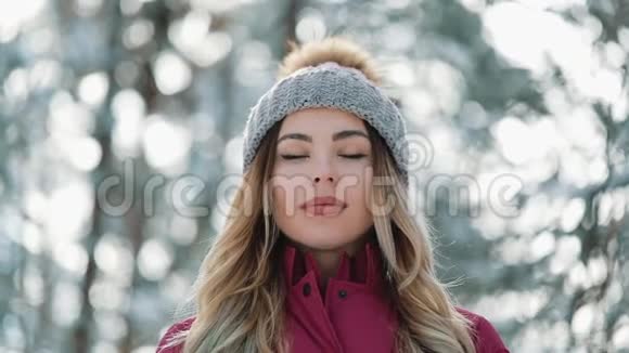 戴着冬帽的漂亮女人喜欢站在外面森林里的雪冬季山林休息视频的预览图