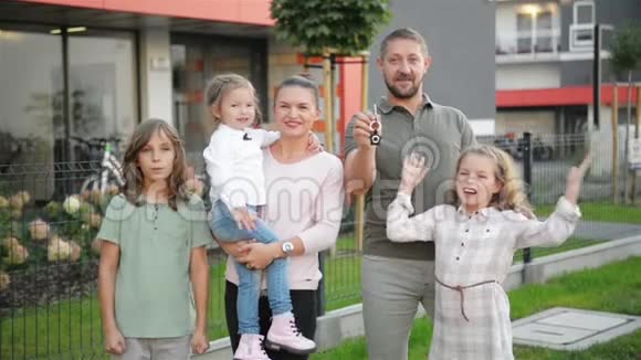 有孩子的家庭看着摄像机站在街道的户外夫妻和孩子买新家房地产业主视频的预览图