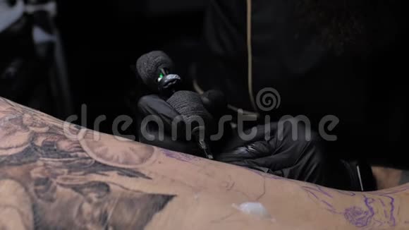 近距离纹身艺术家展示了一个客户背上有油漆的黑色纹身的过程视频的预览图