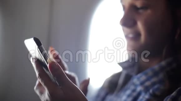 年轻女子在飞机上使用智能手机1920x1080视频的预览图