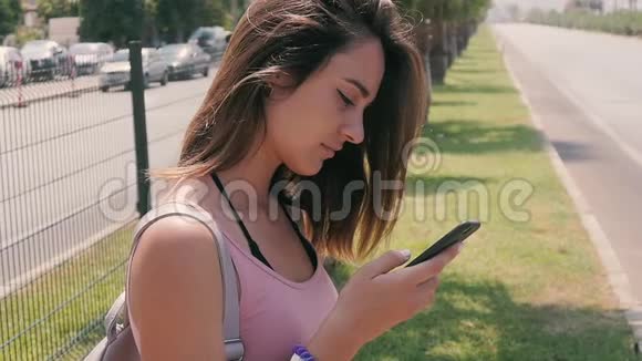 热带度假胜地夏季炎热的城市街道上使用智能手机的年轻女性游客画像视频的预览图