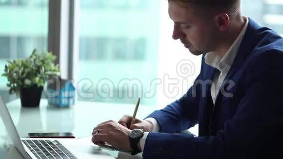 年轻英俊的商人在他办公室的电脑上工作视频的预览图