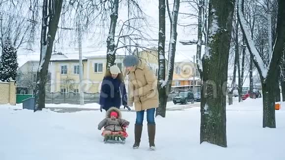 妈妈在冬天把她的小宝宝拉在雪橇上视频的预览图