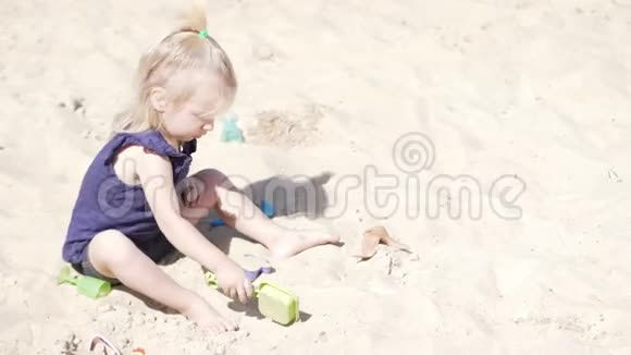沙滩上玩沙子玩具的小女孩视频的预览图
