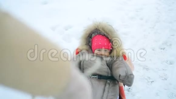 妈妈在冬天把她的小宝宝拉在雪橇上视频的预览图