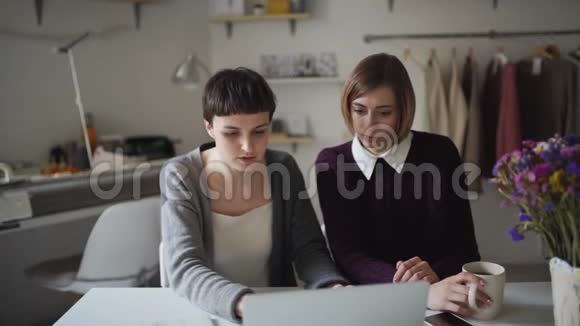 两个女商人正在做背景挂衣服的笔记本视频的预览图