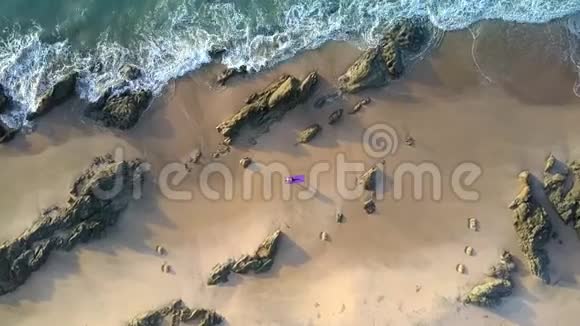泡沫波浪在沙滩上滚动女孩的身影鸟瞰视频的预览图