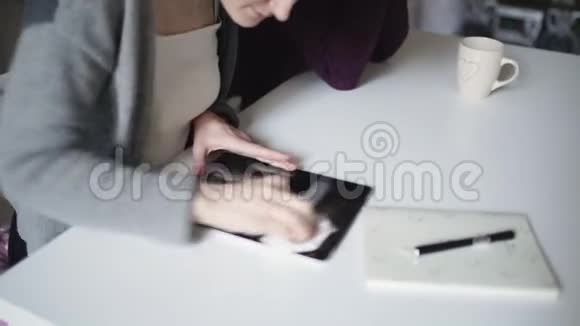 女性手擦拭表面屏幕平板电脑与布躺在桌子上视频的预览图
