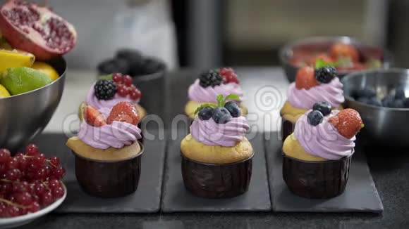 带有奶油馅的纸杯蛋糕用薄荷草莓和蓝莓装饰视频的预览图